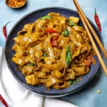 Delicious plate of Drunken Noodles (Pad Kee Mao) garnished with fresh herbs