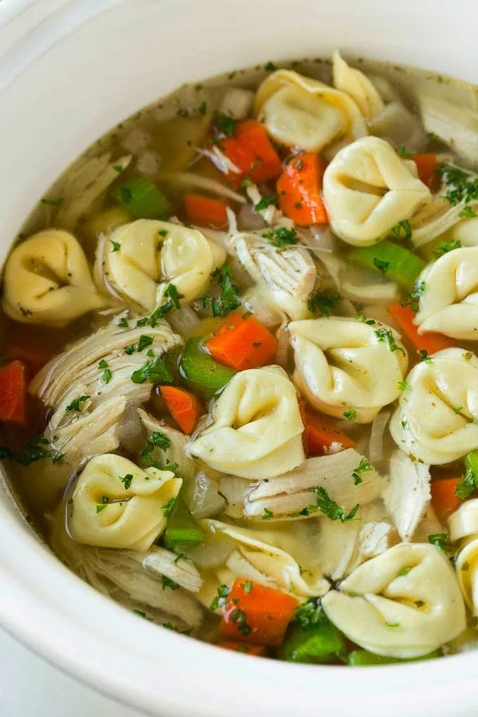 Bowl of Chicken Tortellini Soup with fresh herbs and ingredients