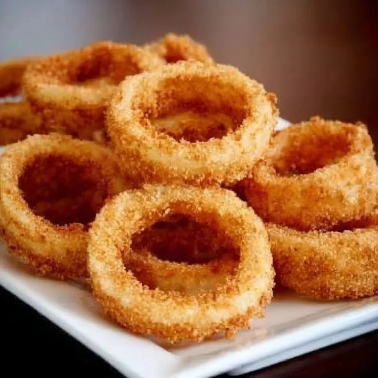 Plate of crispy golden onion rings served with dipping sauce.