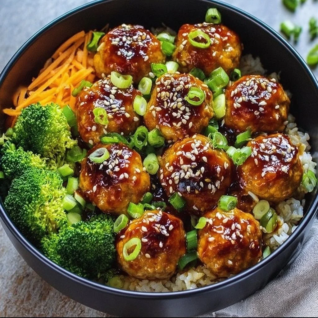 Sweet and spicy sesame chicken meatballs served in a colorful bowl with vegetables.