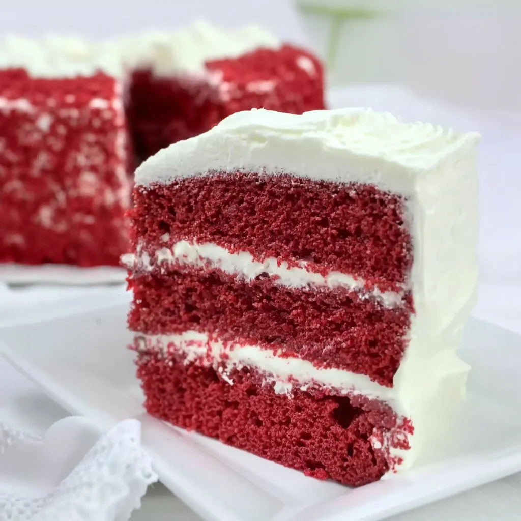 Homemade red velvet cake with cream cheese frosting on a white plate