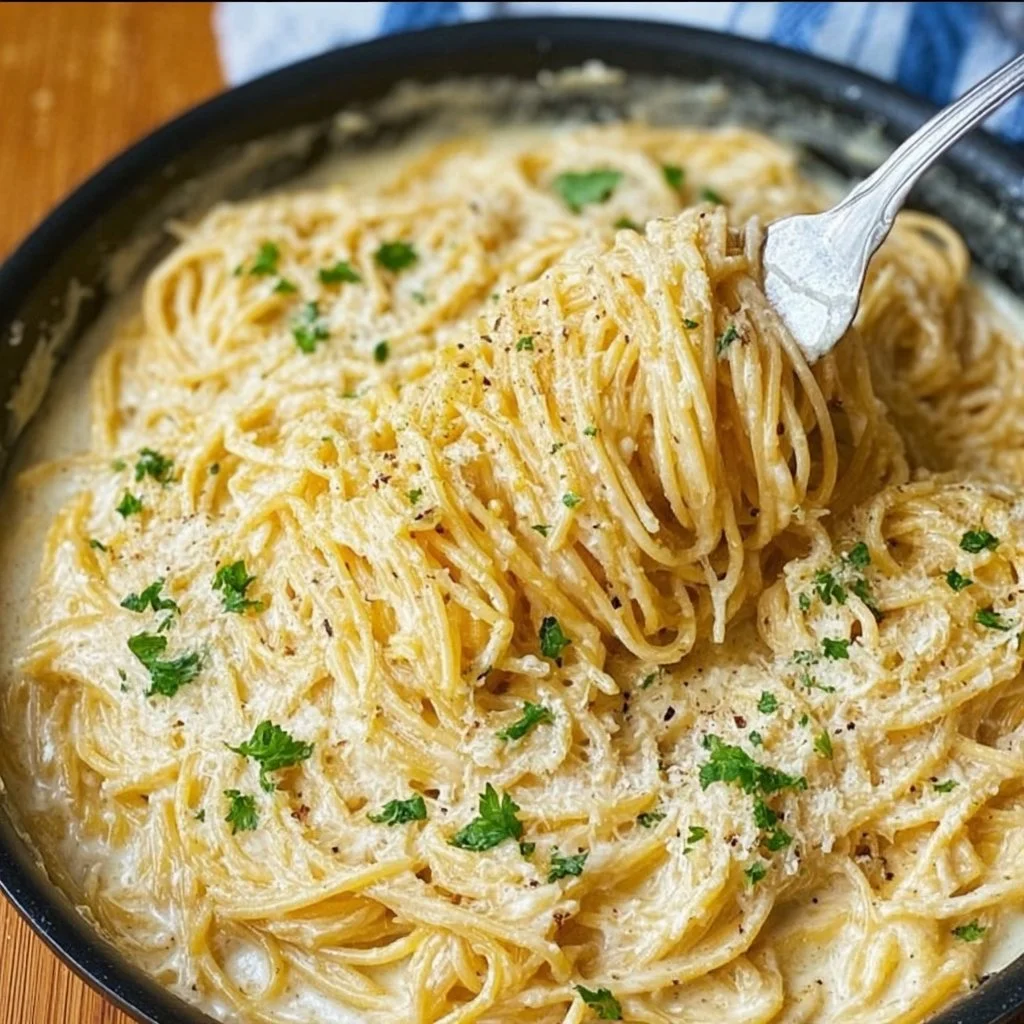 Plate of cheesy garlic parmesan spaghetti topped with herbs and grated cheese
