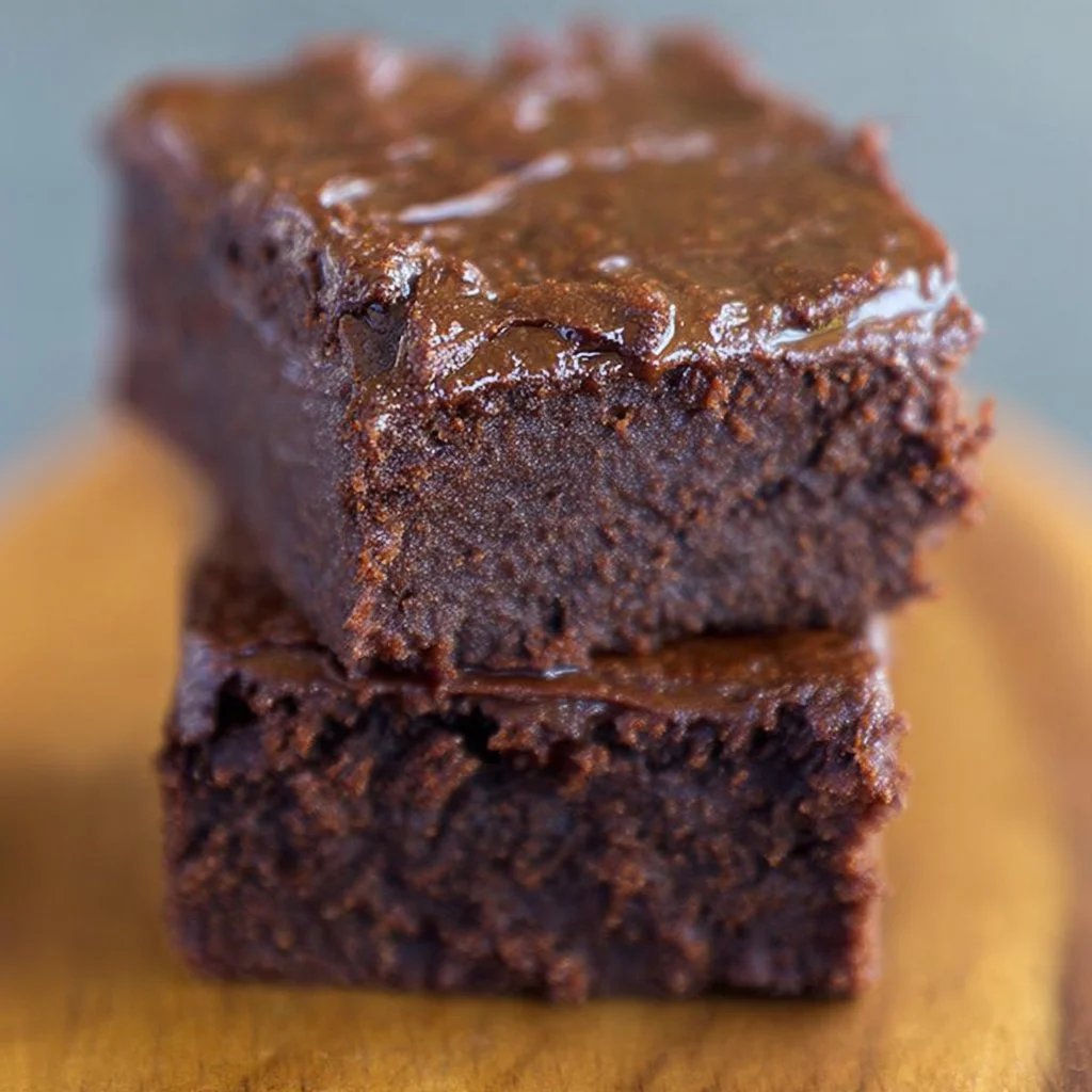 Delicious sweet potato brownies on a plate, topped with chocolate and nuts.