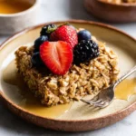 Delicious baked oatmeal served in a bowl with fruits on top.