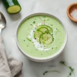 Bowl of cold cucumber soup garnished with herbs, perfect for summer