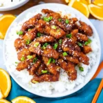 Crispy Ginger Sesame Chicken garnished with sesame seeds and green onions.