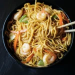 Plate of Hibachi Noodles with Shrimp garnished with vegetables and sauce