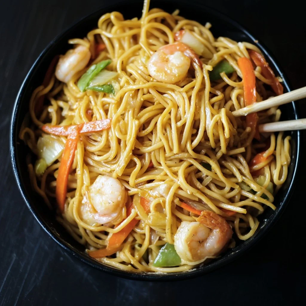 Plate of Hibachi Noodles with Shrimp garnished with vegetables and sauce