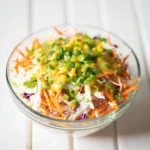 Bowl of quick turmeric chicken salad garnished with fresh herbs and spices