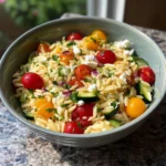 A vibrant orzo salad with fresh vegetables and herbs, showcasing the art of flavor.