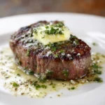 Juicy garlic butter steak garnished with herbs on a wooden cutting board