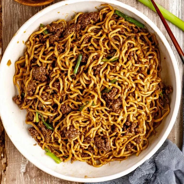 Delicious chili garlic beef noodles served in a bowl with fresh herbs.
