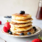 Fluffy Greek yogurt pancakes served with fresh fruit and maple syrup