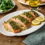 Pesto salmon dish garnished with fresh basil and served with vegetables