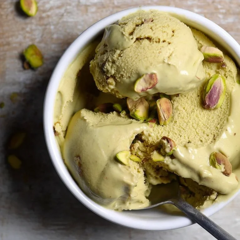 Delicious homemade pistachio ice cream in a bowl with pistachios scattered around.