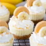 Mini banana pudding cheesecakes topped with whipped cream and bananas.