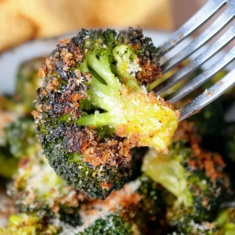 Bowl of Parmesan Roasted Broccoli garnished with cheese and herbs on a table