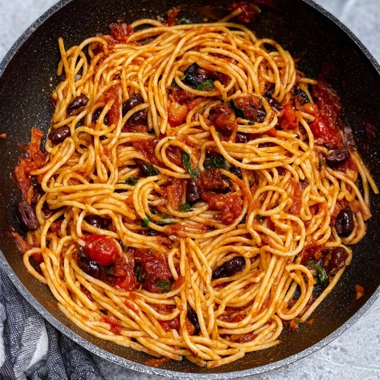 A plate of Pasta Puttanesca with olives and tomatoes, showcasing its colorful ingredients.
