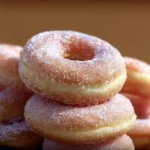 Freshly made yeast doughnuts on a cooling rack, showcasing their fluffy texture.
