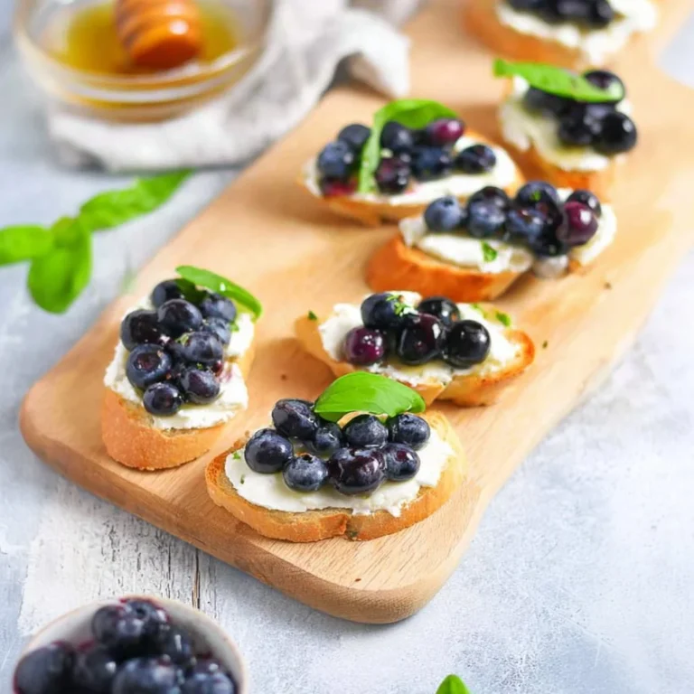 Blueberry goat cheese crostini topped with fresh blueberries and herbs