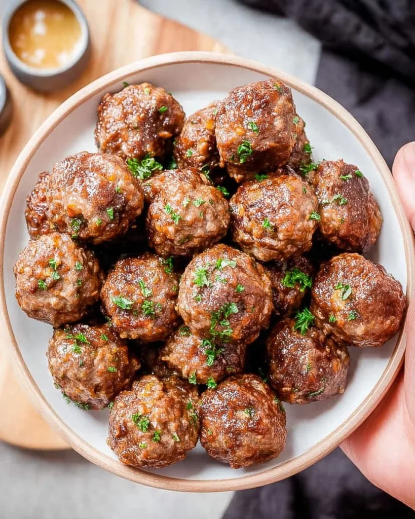 Golden brown air fryer meatballs served with marinara sauce on a plate