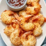 Plate of baked coconut shrimp garnished with fresh herbs
