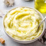 Boursin mashed potatoes topped with herbs in a white bowl