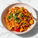 Colorful carrot noodles served in a bowl with fresh herbs