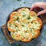 Cheesy spinach and artichoke pinwheels on a platter, ready to serve