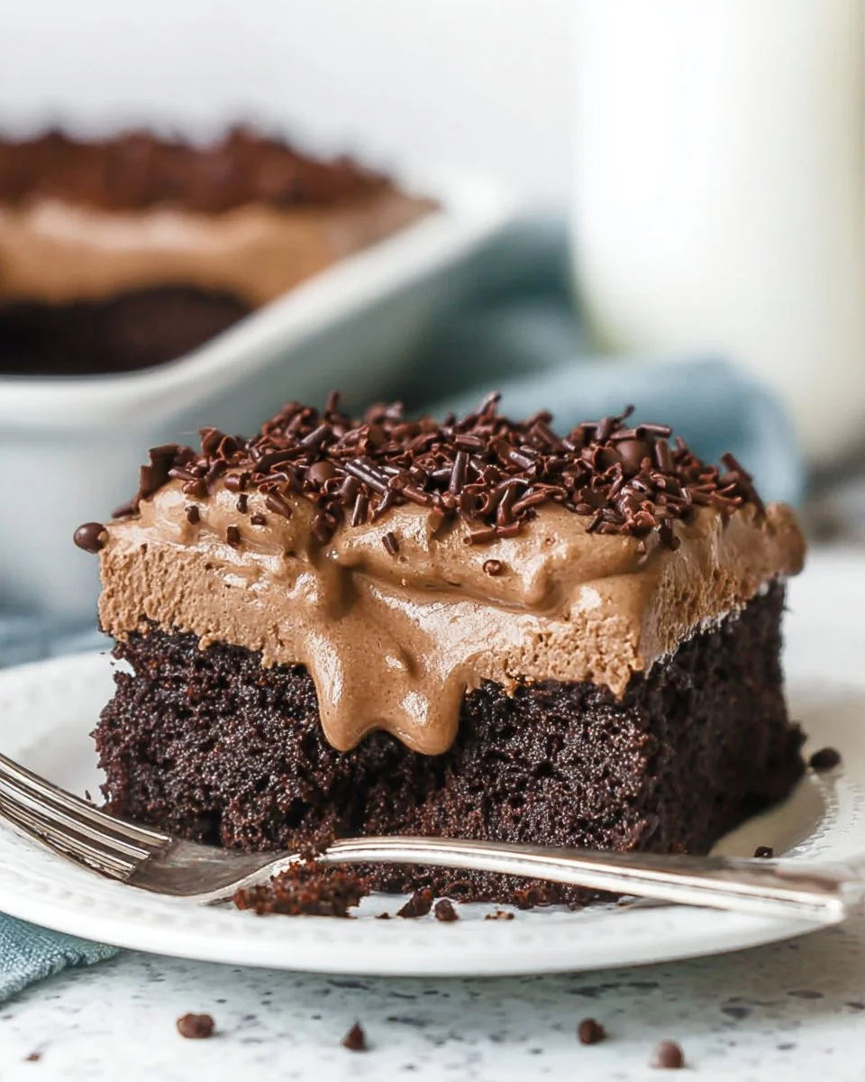 Delicious Chocolate Poke Cake topped with creamy frosting and drizzled chocolate sauce