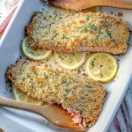 Crispy baked salmon fillet garnished with herbs and lemon on a plate