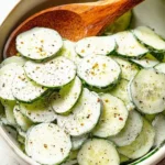 Cucumber salad topped with creamy sour cream dressing in a bowl
