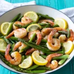 Plate of lemon asparagus shrimp garnished with lemon slices and herbs