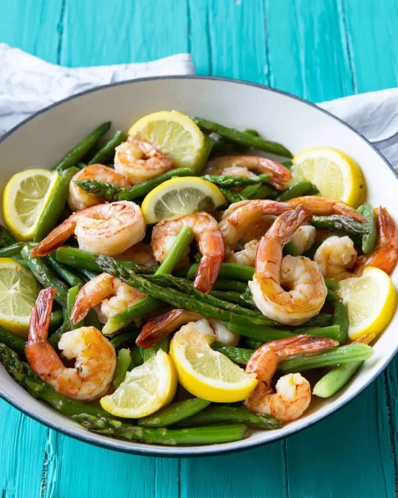 Plate of lemon asparagus shrimp garnished with lemon slices and herbs