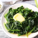 Plate of Garlic Sauteed Spinach garnished with garlic cloves