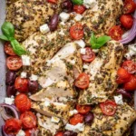 Juicy Greek Baked Chicken Breast garnished with herbs and lemon