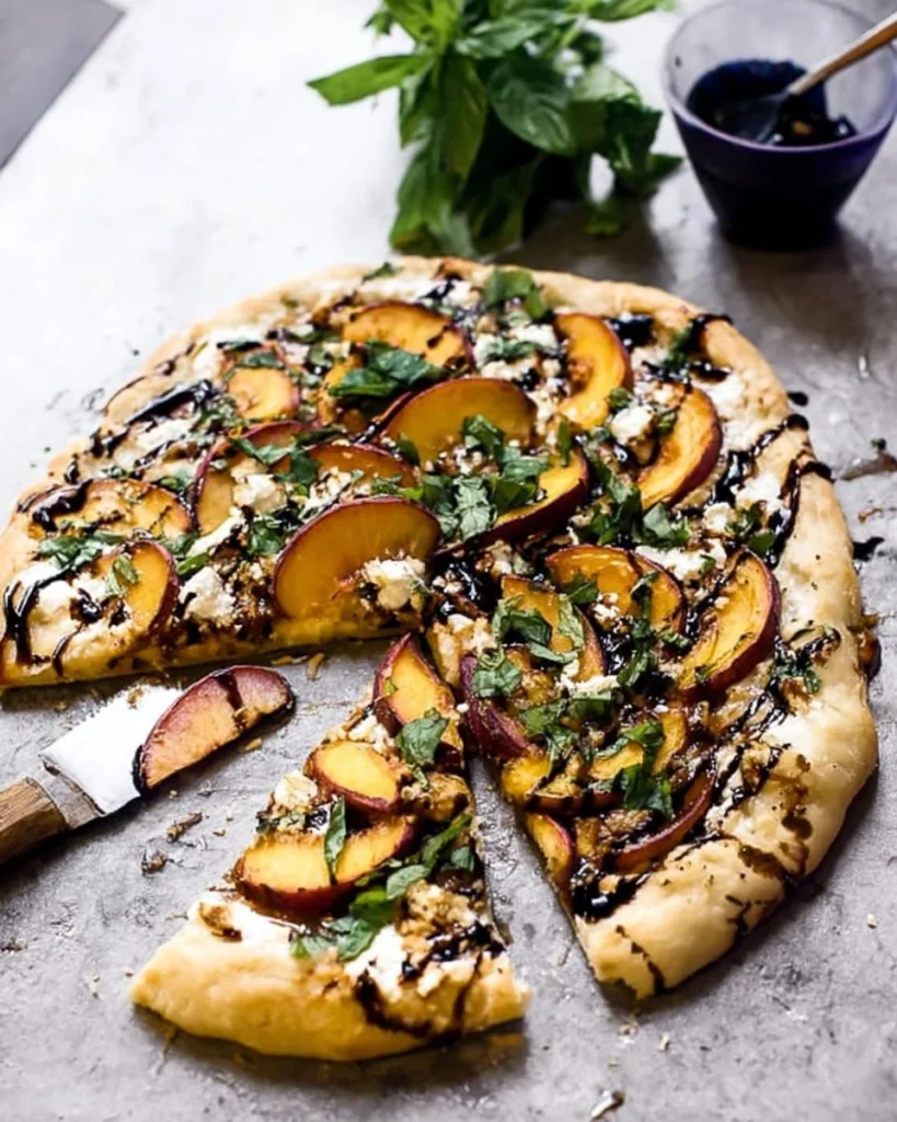Grilled Peach Pizza with basil and vegan goat cheese on a wooden board.