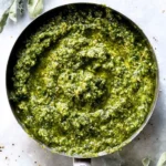 Bowl of vibrant green kale pesto with pasta and pine nuts