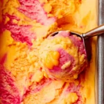 Delicious mango strawberry frozen yogurt served in a bowl with a spoon.