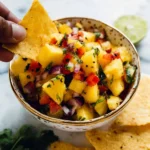 Fresh pineapple salsa served in a bowl with cilantro and lime