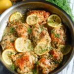 Skillet lemon dill chicken thighs served with fresh herbs and lemon slices.