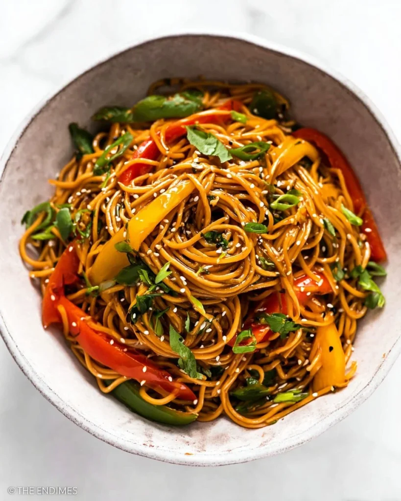 Plate of flavorful soy ginger noodles garnished with fresh vegetables