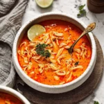 Delicious bowl of spicy chicken soup garnished with herbs and spices