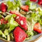 Fresh strawberry avocado salad with greens and dressing on a plate