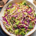 Colorful bowl of fresh broccoli slaw with carrots and dressing