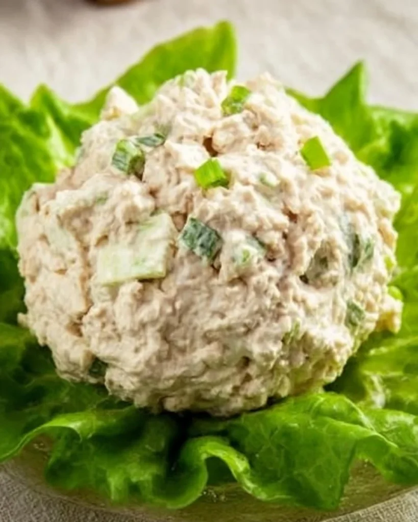A bowl of Classic Carol Chicken Salad garnished with fresh herbs.