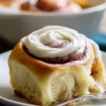Cream cheese frosting drizzled over freshly baked cinnamon rolls