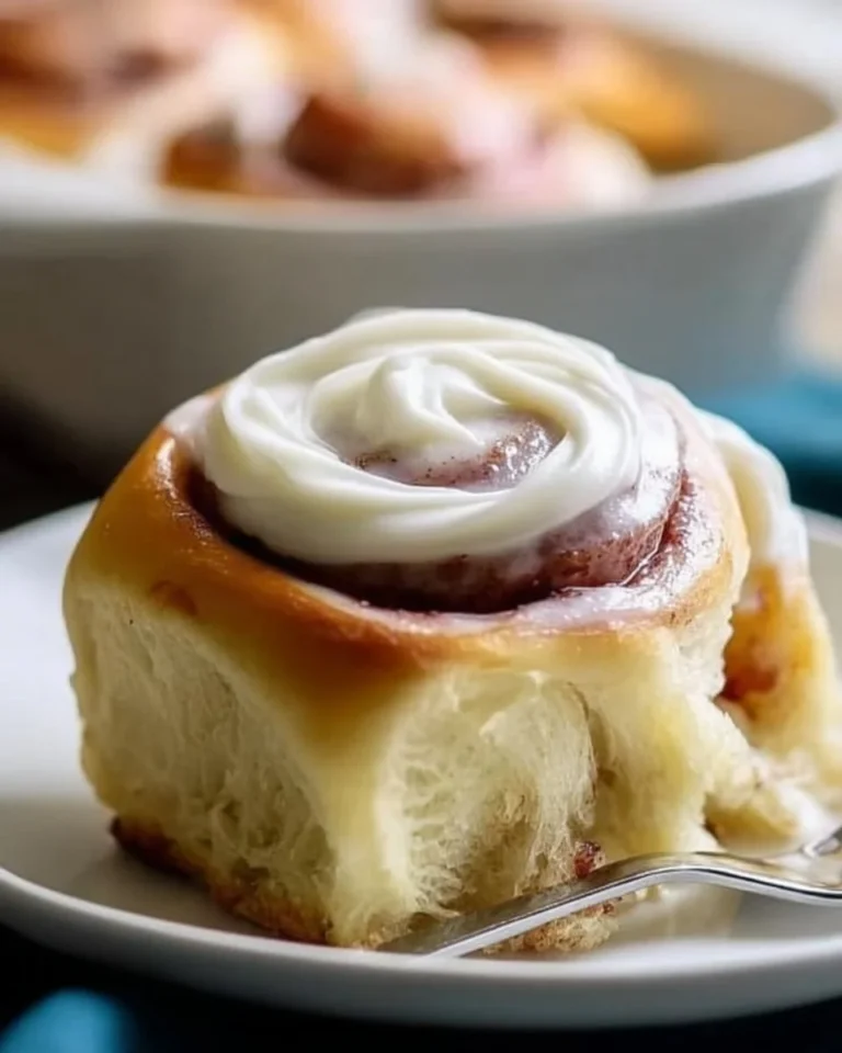 Cream cheese frosting drizzled over freshly baked cinnamon rolls