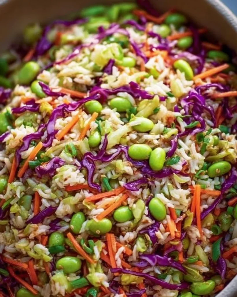A vibrant bowl of Crunchy Asian Rice Salad with fresh vegetables and sesame seeds.