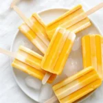 Dreamy creamy mango pops served on a stick, perfect for summer treats.